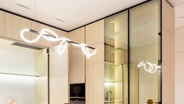 A modern dining area with a glass table, black chairs, and a unique light fixture. - Green House (Poti)