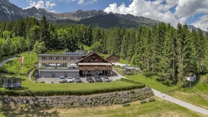 A hotel with a parking lot, outdoor seating, and a view of mountains. - Sweet Cherry Boutique & Guesthouse Tyrol (Innsbruck)