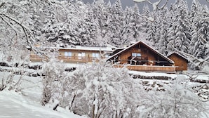 A wooden cabin with a balcony, surrounded by snow-covered trees. - Sweet Cherry Boutique & Guesthouse Tyrol (Innsbruck)
