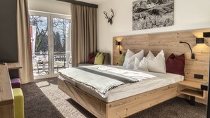 A modern bedroom with a wooden bed, a mounted deer head, and a mountain landscape painting. - Sweet Cherry Boutique & Guesthouse Tyrol (Innsbruck)