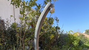 Een modern waterkunstwerk buiten, met een golvend ontwerp, geplaatst naast een houten terras en omringd door weelderige beplanting.