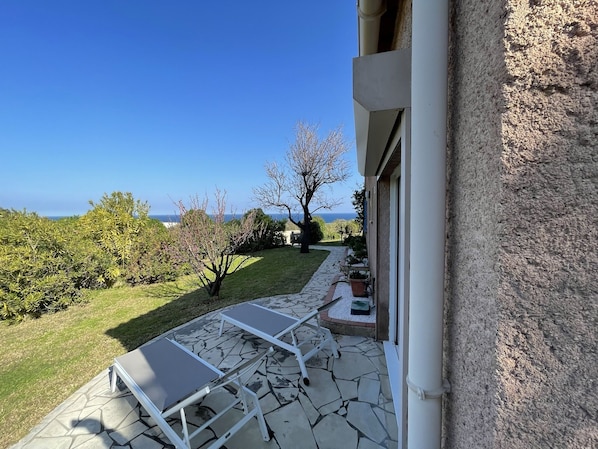 A patio with a table and chairs, a stone pathway, and a view of the sea.