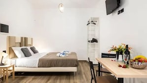 Un dormitorio moderno con una cama, mesita de noche y televisor montado en la pared.