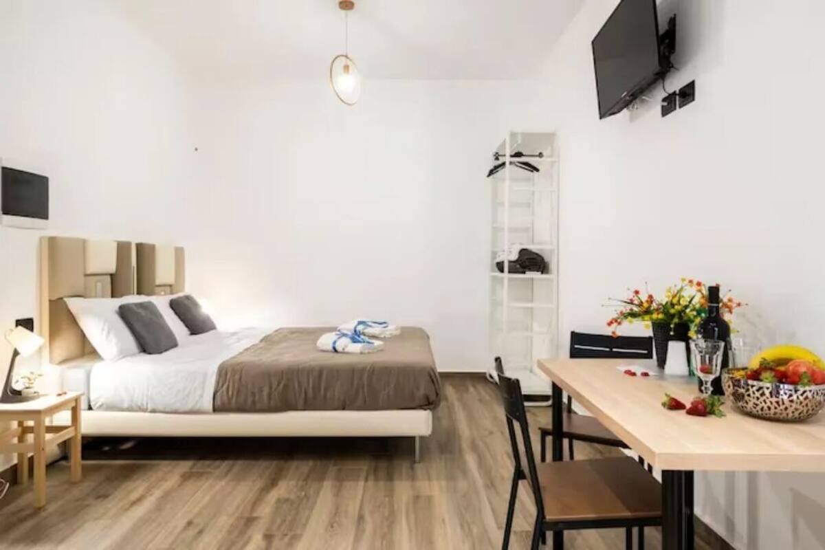 A modern bedroom with a bed, bedside table, and a TV mounted on the wall.