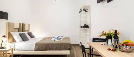 A modern bedroom with a bed, bedside table, and a TV mounted on the wall.