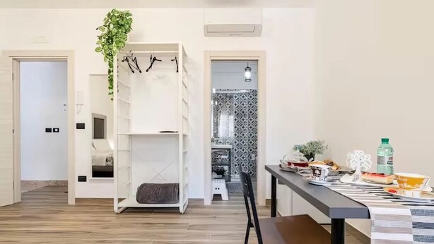 Una cocina moderna con comedor, suelo de madera y un armario blanco con estantes.