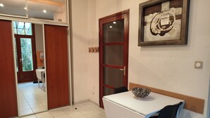 Una stanza con una scrivania bianca, una sedia nera, una porta in legno con pannelli di vetro e un quadro appeso al muro.