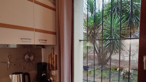 Una cucina con vista su un giardino, una bollita, una macchina del caffè e utensili a parete.