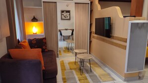 Un soggiorno moderno con divano, televisione e zona pranzo con tavolo e sedie.