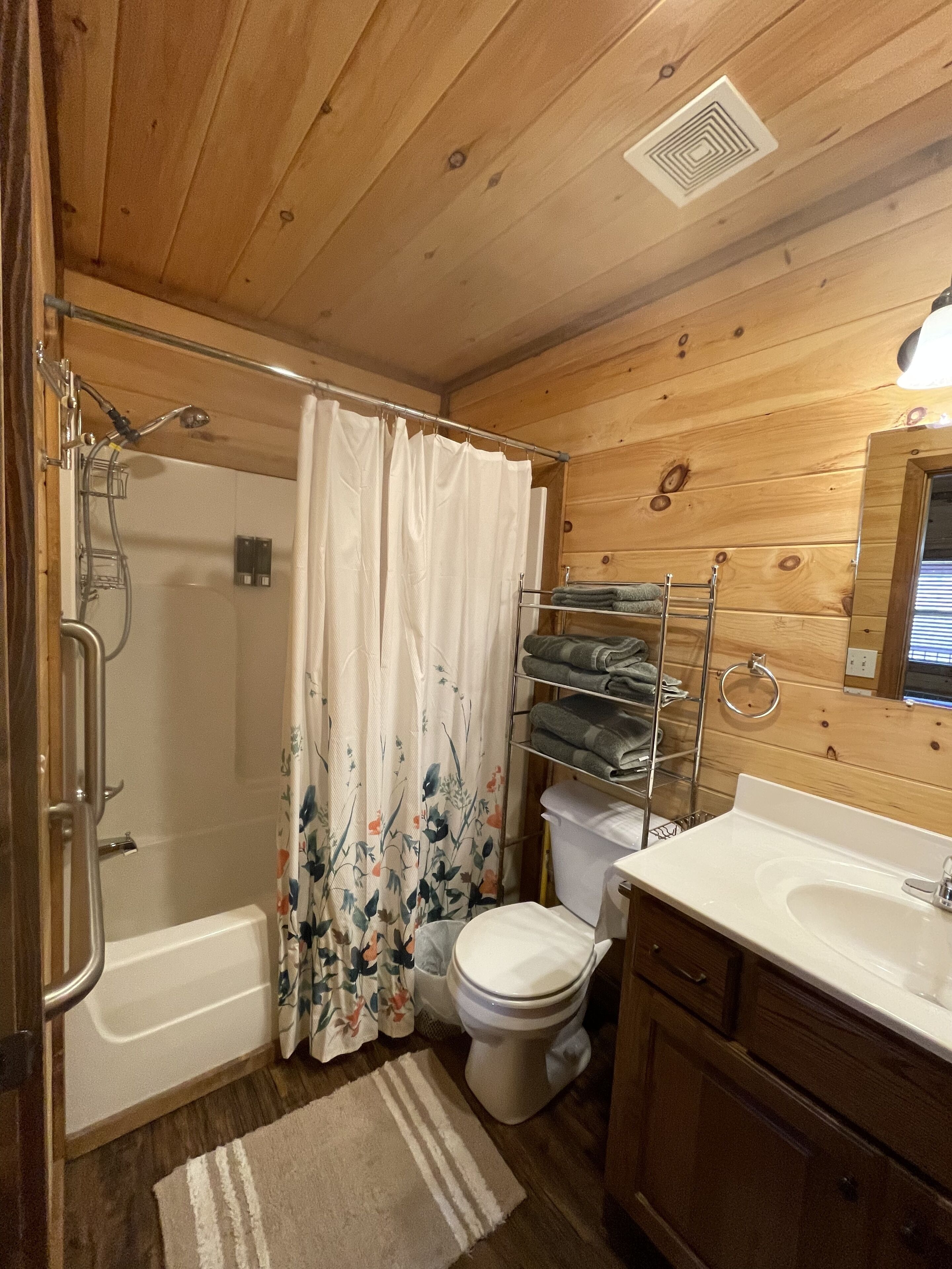 Een houten badkamer met een badcabine, toilet en wastafel.