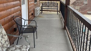 A wooden cabin with a covered porch, a bench, and a table with a patterned tablecloth.