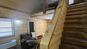 A wooden interior with a staircase, a sofa, and a dining table.