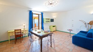 A room with a dining table, chairs, a sofa, a TV, and a window with curtains. - House "Le Anfore" - Amalfi Coast (Conca dei Marini)