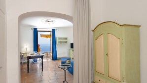 A room with a dining area, a bed, a wardrobe, and a view of the sea. - House "Le Anfore" - Amalfi Coast (Conca dei Marini)