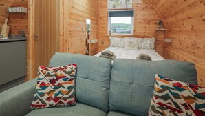 Ein gemütliches Blockhauszimmer mit Bett, Sofa und Fenster mit Blick auf eine Landschaft.