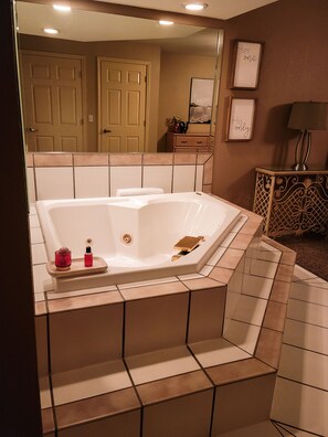 A bathroom with a large bathtub, a vanity with a mirror, and a framed picture on the wall.