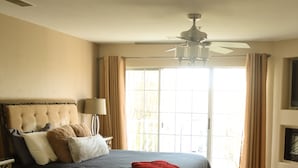A bedroom with a large bed, a ceiling fan, and a view of the outdoors through a window. - Romantic King Suite With Jetted Tub For 2 (Branson)