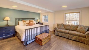 Une chambre à coucher comprenant un lit, une table de chevet, une commode, une fenêtre et un canapé.