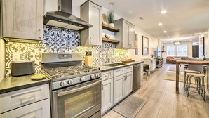 A modern kitchen with stainless steel appliances, patterned backsplash, and light wood flooring.