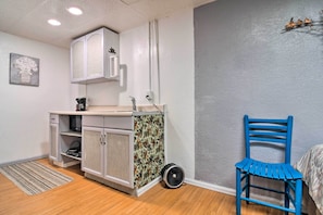 A compact kitchen with white cabinets, a microwave, and a small sink. There's a blue chair and a patterned rug on the floor. - Vacation Rental Near Boyd Lake, Colorado! (Loveland)
