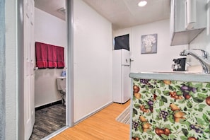 A compact kitchen with a refrigerator, sink, and a fruit-patterned backsplash. - Vacation Rental Near Boyd Lake, Colorado! (Loveland)