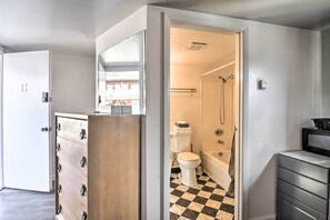 Un baño con piso a cuadros blanco y negro, un inodoro, una ducha y un lavamanos.