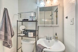 Ein Badezimmer mit einem weißen Waschbecken, einem Spiegel, einem Handtuchhalter und einem Ablagebereich mit Toilettenartikeln.