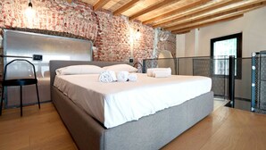 A bedroom with a large bed, wooden beams, a brick wall, and a window. - Lancetti Stylish Loft (Milan)