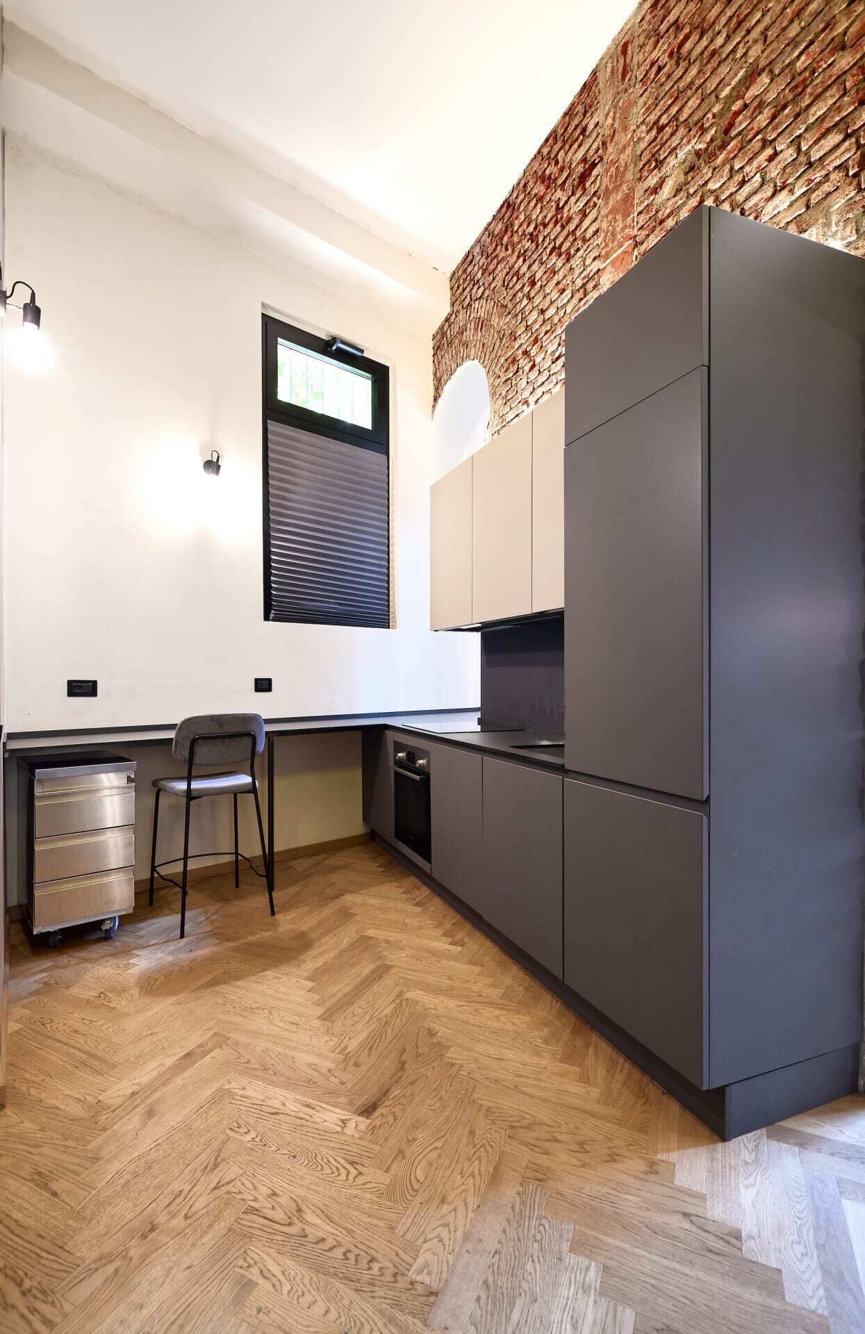 Eine moderne Küche mit Fischgrätparkett, einem eingebauten Geschirrspüler und einem großen Kühlschrank.