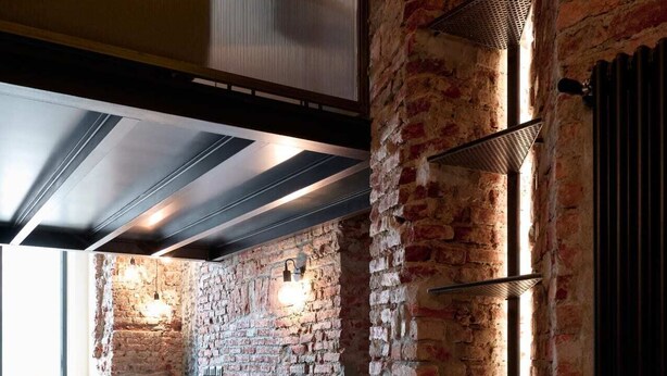 A modern kitchen with exposed brick walls, a herringbone-patterned floor, and built-in cabinetry. - Lancetti Stylish Loft (Milan)