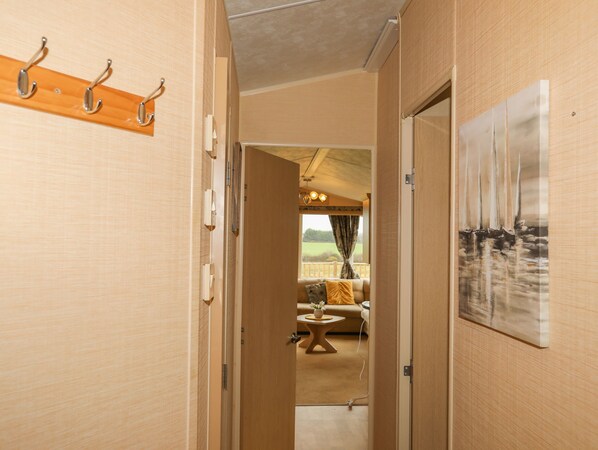 A hallway leading to a living area with a sofa, a small table, and a painting on the wall.