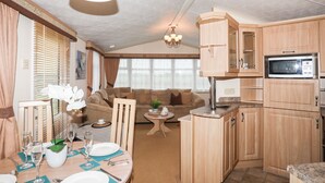 A compact living space with a dining area, kitchenette, and seating area. - Mountain View Lodge 2 (Holyhead)