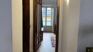Un pasillo estrecho con puertas de madera y una alfombra colorida en el suelo.
