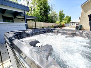 A hot tub with a built-in seat and a small waterfall feature, surrounded by a brick wall and a wooden deck. - Sanderson House (Cleator Moor)