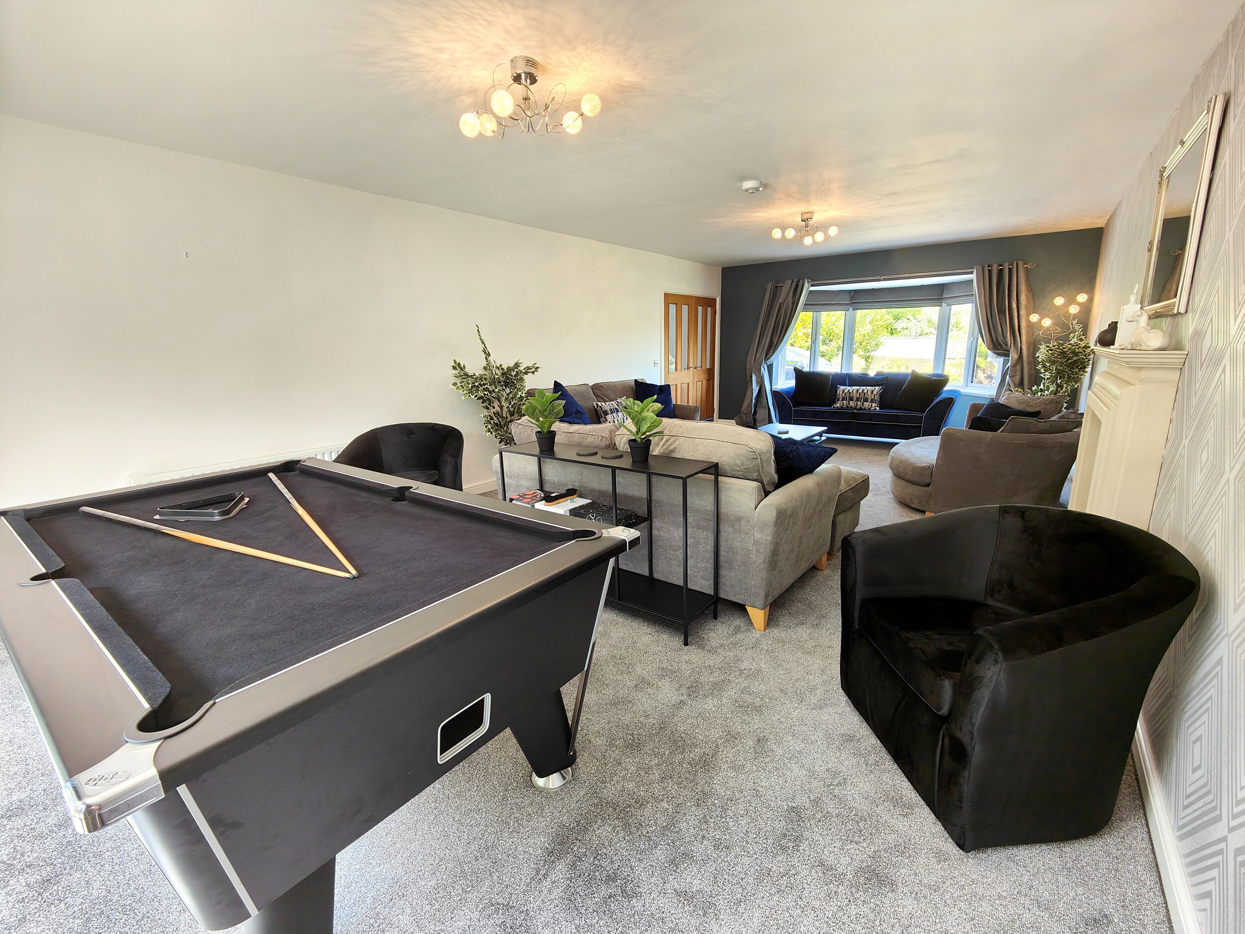 A pool table in a living room with a sofa and a fireplace.