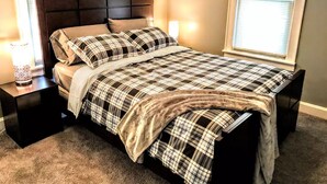 A bedroom with a bed, nightstands, a lamp, and a window.