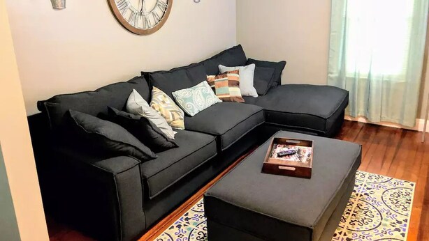 A modern living room with a sectional sofa, a coffee table, and decorative plants.