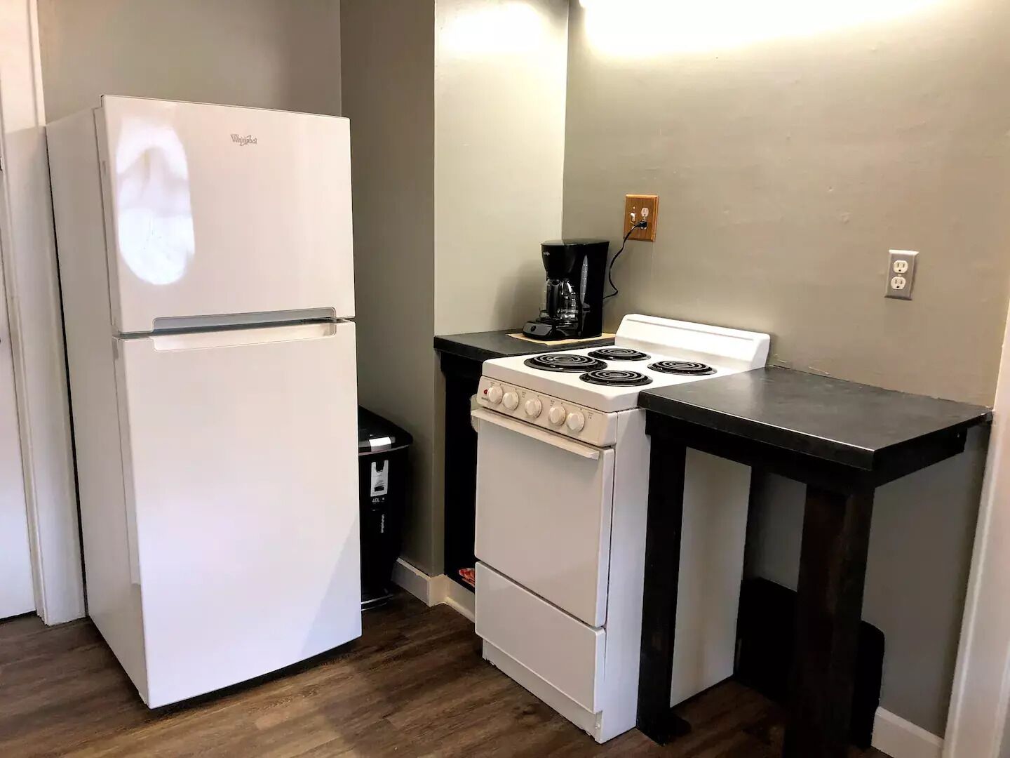 A compact kitchen with a white refrigerator, a stove, and a coffee maker.