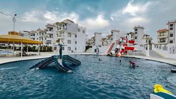 A swimming pool with a water slide and a children's play area.