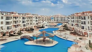 A resort with multiple white buildings, a central pool area, and a clear blue sky. - Sharm Hills Resort (Sharm El Sheikh)