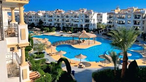 A resort with a large swimming pool, palm trees, and modern buildings. - Sharm Hills Resort (Sharm El Sheikh)