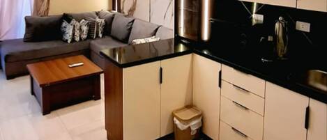 Una sala de estar moderna con un sofá, una mesa de centro y una cocina con armarios y una encimera.