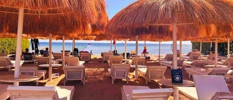 Privat strand, parasoller, volleyboll och strandbarer