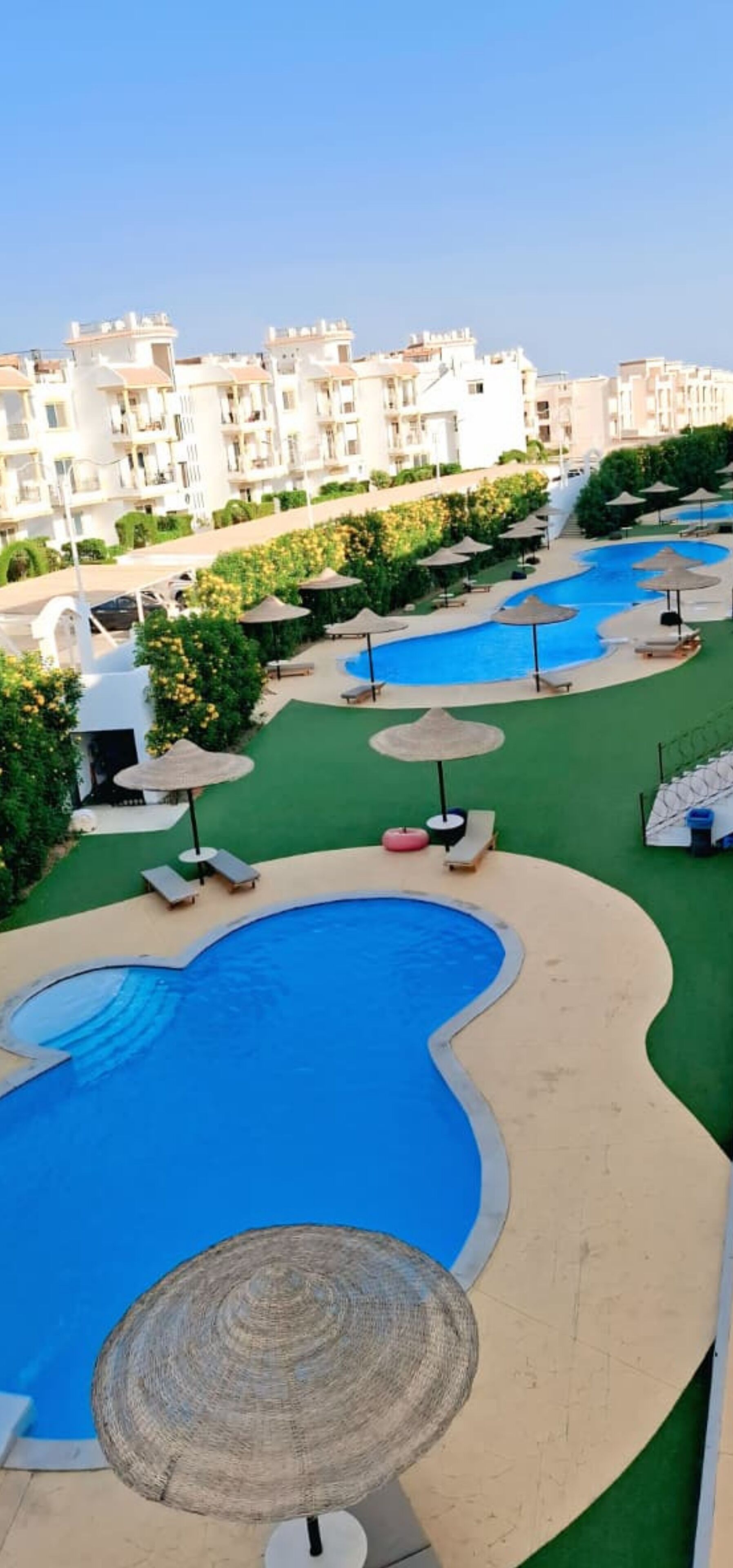 Ett poolområde på ett semesterhotell med flera pooler, solstolar och parasoller.