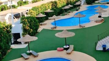 Ett poolområde på ett semesterhotell med flera pooler, solstolar och parasoller.
