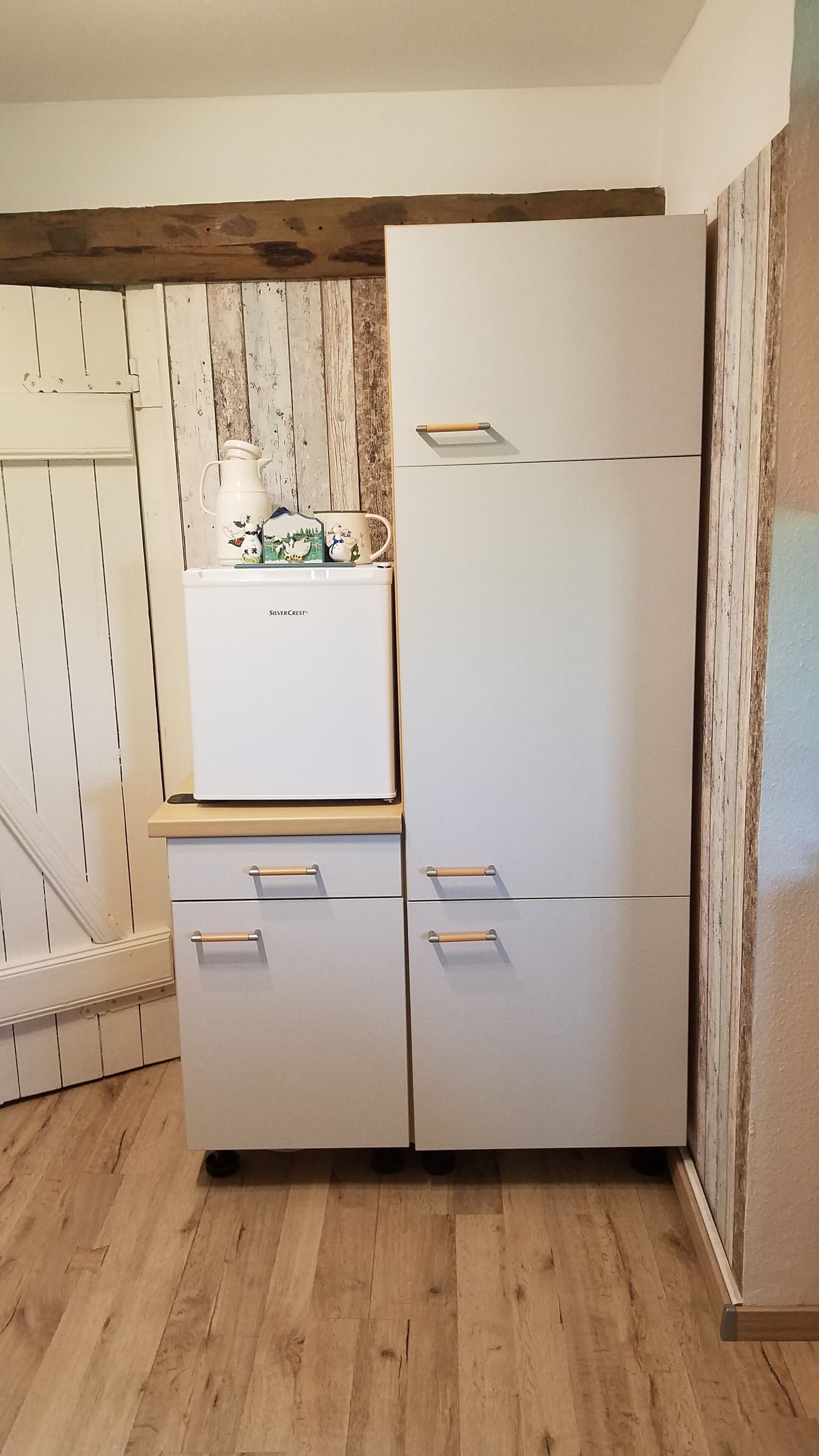 Uma cozinha compacta com geladeira, pia e bancada de madeira.