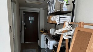 A compact hotel room with a kitchenette, a small seating area, and a door leading to another room. - Shin-osaka 1109 (Osaka)