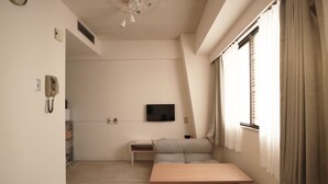 A modern, minimalist room with a wooden table, a sofa, and a TV mounted on the wall. - Shin-osaka 1109 (Osaka)