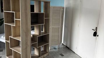 Une pièce avec un sol carrelé, une étagère en bois, une porte blanche et un mur bleu.