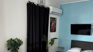 A modern bedroom with a sofa, a bed, a TV, and two potted plants. - Urban Zen Appart in the city center✨ (Pointe-à-Pitre)